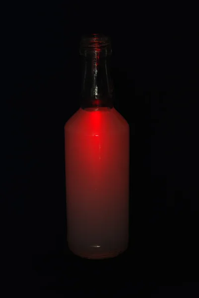 Garrafa com uma bebida vermelha no fundo preto — Fotografia de Stock