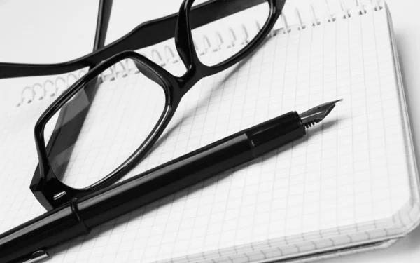 Óculos e caneta, no bloco de notas — Fotografia de Stock