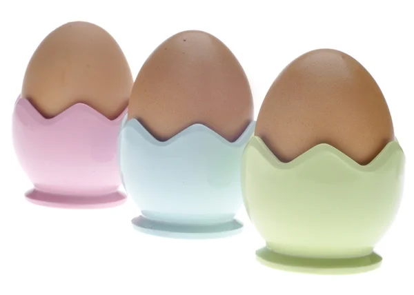 Tre tazze di uova pastello con uova marroni — Foto Stock
