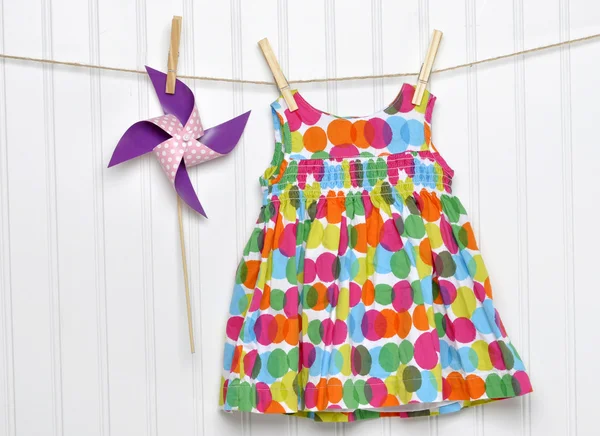 Bebek elbisesi ve fırıldak bir clothesline üzerinde Telifsiz Stok Fotoğraflar