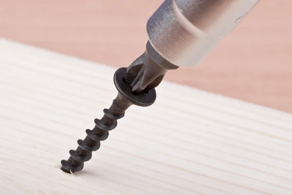 stock image Closeup image of screwdriver and single screw in board.