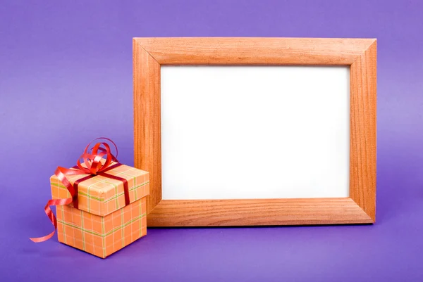 Wooden photo frame and orange gift box with red ribbon on blue b — Stock Photo, Image