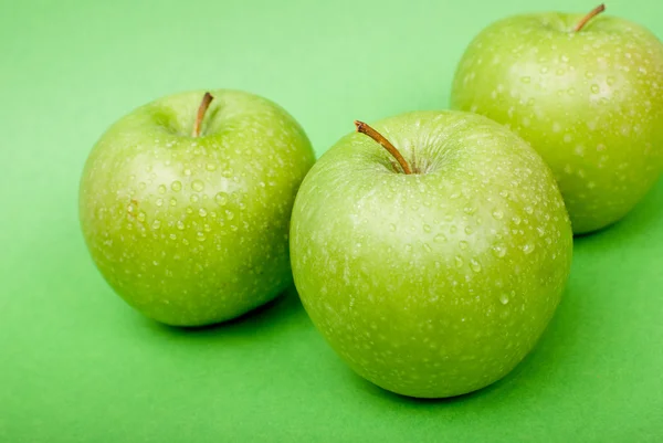 Ripe green apples with water drops on green background — Stock Photo, Image
