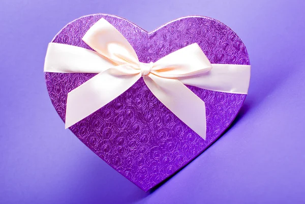 Single heart gift box with ribbon on blue background. — Stock Photo, Image