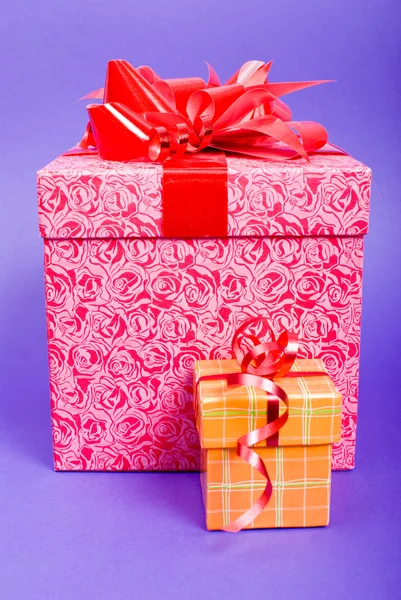 Оранжевая и розовая подарочная коробка с красной лентой на синем фоне . — стоковое фото