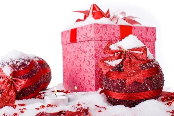 De doos van de gift van Kerstmis in de sneeuw met rode ballen en kaarsen — Stockfoto