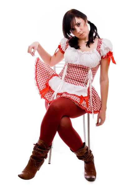坐在一张椅子上白色背景上的一件红色连衣裙的性感女人 — 图库照片