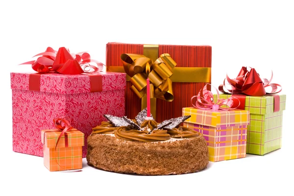 Kuchen mit einer Kerze und Geschenken in Schachteln auf weißem Hintergrund — Stockfoto