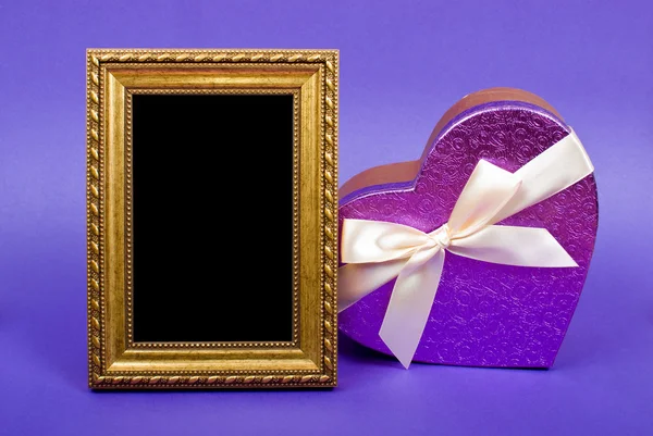 Gold Fotorahmen und Herz Geschenkbox mit Band auf blauem Hintergrund — Stockfoto