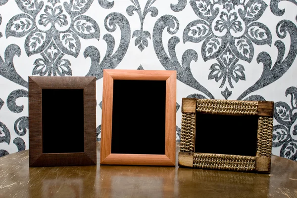 Drie houten fotoframes op oude tabel op vintage behang terug — Stockfoto