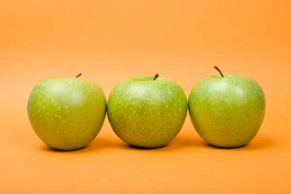 Maçãs verdes maduras no fundo laranja — Fotografia de Stock