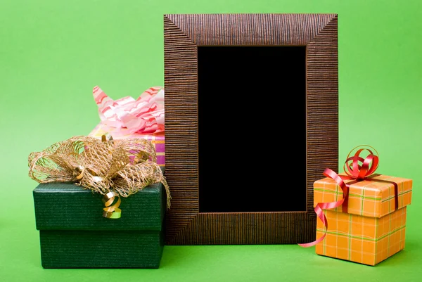 Marco de fotos de madera y cajas de regalo con cintas sobre fondo verde — Foto de Stock