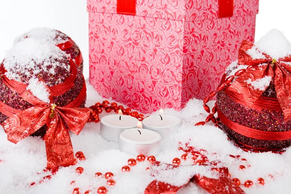 De doos van de gift van Kerstmis in de sneeuw met rode ballen en kaarsen — Stockfoto