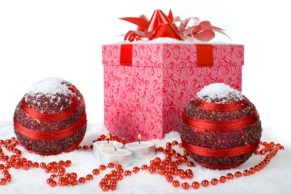Weihnachtsgeschenkbox im Schnee mit roten Kugeln und Kerzen — Stockfoto