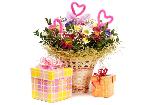 Beautiful bouquet in the basket and present boxes on a white bac — Stock Photo, Image