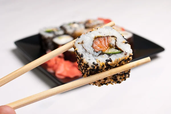 Sushi em uma chapa preta na mesa branca . — Fotografia de Stock