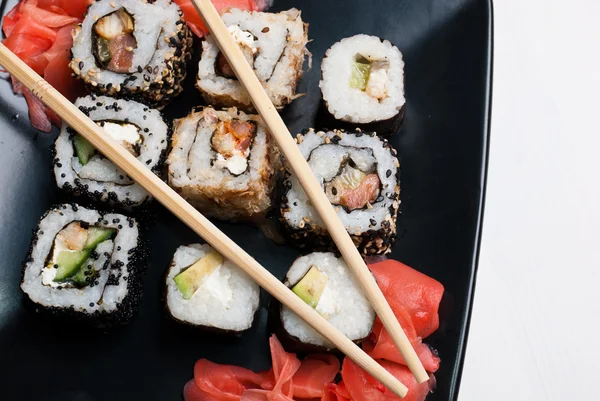 stock image Sushi on a black plate on white table.