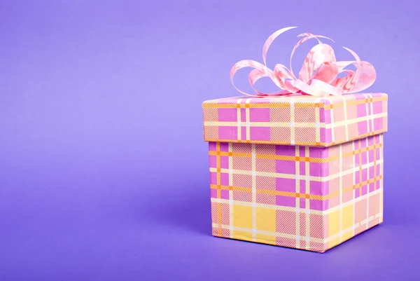 蓝色背景上的粉红丝带单黄色礼品盒. — 图库照片
