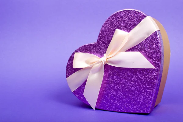 Single heart gift box with ribbon on blue background. — Stock Photo, Image
