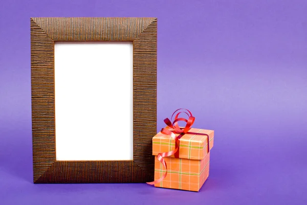 Деревянная рамка и оранжевая подарочная коробка с красной лентой на голубом — стоковое фото