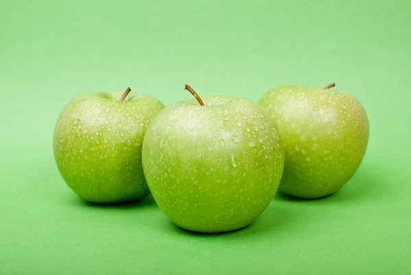 Zralé zelená jablka s vodou klesne na zeleném pozadí — Stock fotografie
