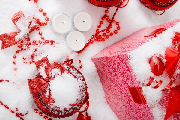 Vánoční dárková krabička na sněhu s červenou koulí a svíčky — Stock fotografie