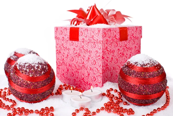 Christmas gift box in the snow with red balls and candles — Stock Photo, Image