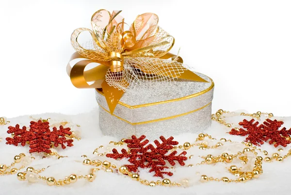 Confezione regalo natalizia cuore argento con nastro dorato sulla neve su un Immagini Stock Royalty Free
