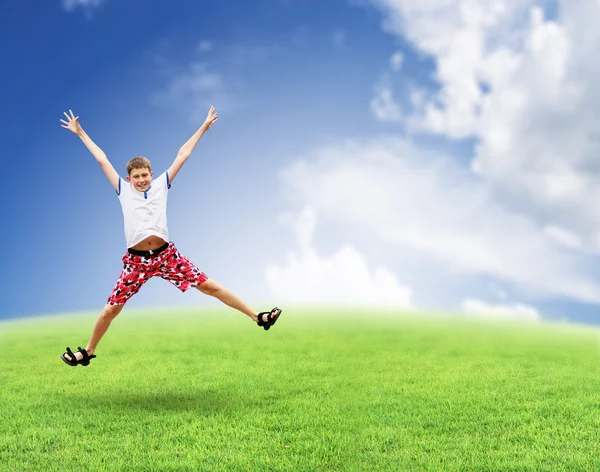 Skoki chłopiec na trawie. niebo. Obraz Stockowy