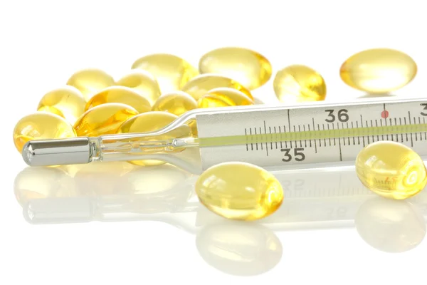 Termômetro médico e comprimidos amarelos — Fotografia de Stock