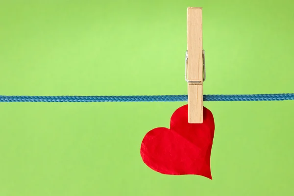 Red heart hung over a green background — Stock Photo, Image