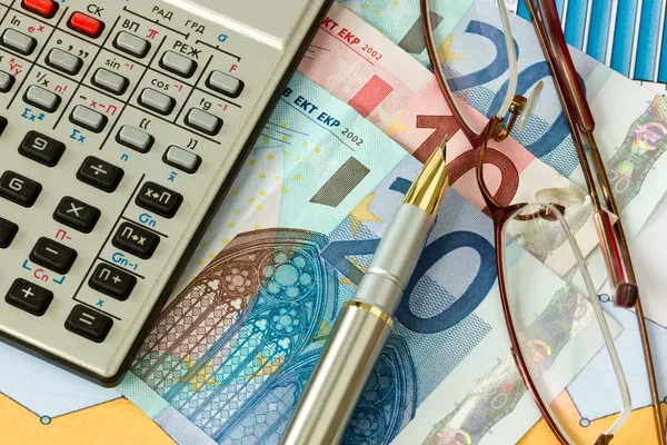 Óculos, caneta, calculadora e dinheiro europeu — Fotografia de Stock