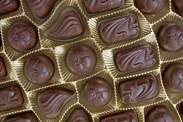 Choklad praliner i en gyllene låda — Stockfoto