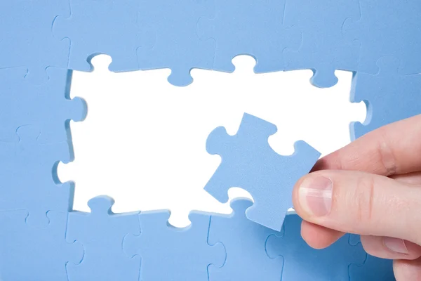 Hand collecting blue puzzle — Stock Photo, Image