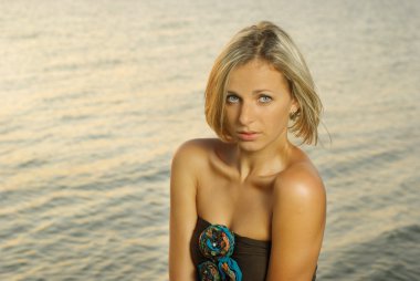 Portrait of a fashionable young women against sunset on a river