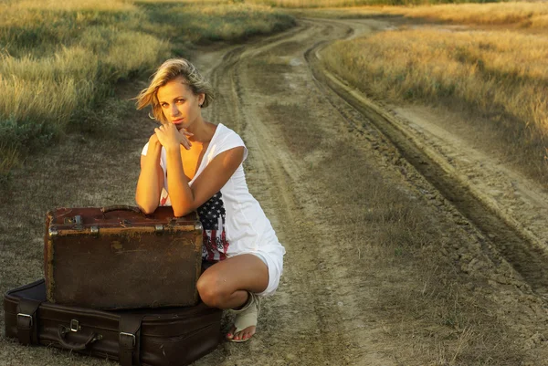 Chica bonita con una maleta en un camino rural — Foto de Stock