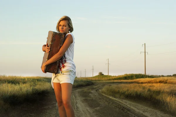 Chica bonita con una maleta en un camino rural —  Fotos de Stock