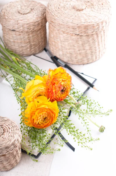 Gele bloemen, rieten manden en een notebook — Stockfoto