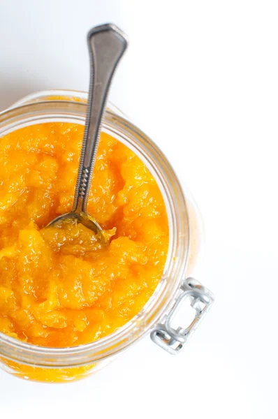 Engarrafamento de laranja em um jarro em um contexto branco — Fotografia de Stock