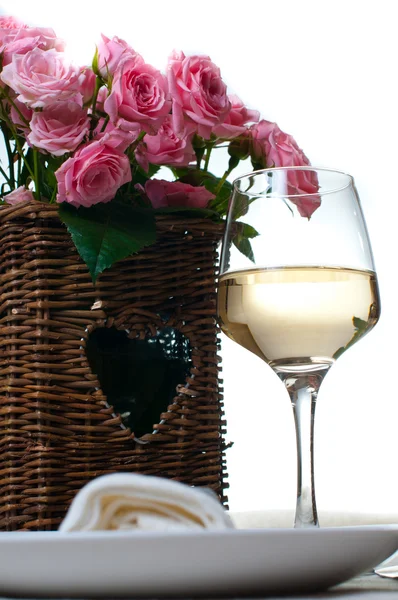 Copa de vino blanco y una cesta de rosas — Foto de Stock