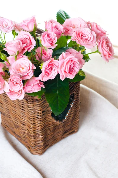 Rosas rosa em uma cesta de vime e tecido de linho — Fotografia de Stock