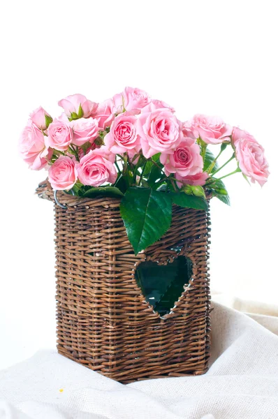 Růžové růže v proutěný koš a prádlo tkanina — Stock fotografie