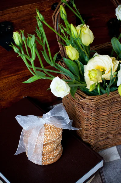 Квіти в плетеному кошику, печиво, книга — стокове фото