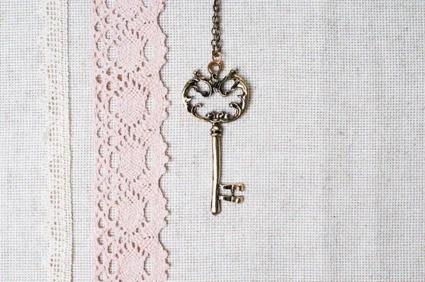 Key, natural linen fabric and lace — Stock Photo, Image