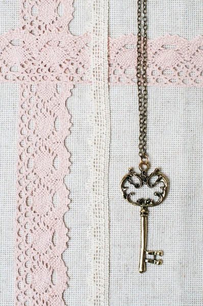 Key, natural linen fabric and lace — Stock Photo, Image