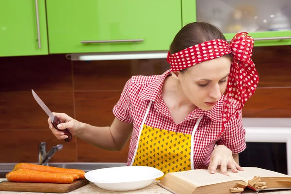 Kvinnan i köket med kniv receptbok — Stockfoto