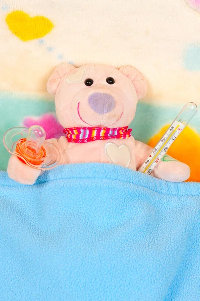 หมีเท็ดดี้นอนบนเตียงด้วยเครื่องวัดอุณหภูมิ — ภาพถ่ายสต็อก