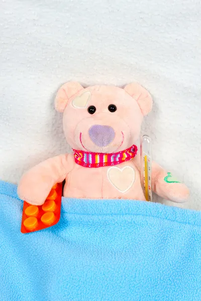 Urso de pelúcia deitado na cama com termômetro — Fotografia de Stock