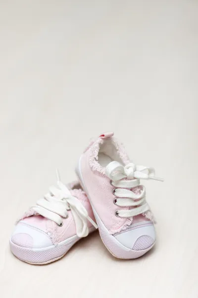 Little girlie baby shoes on a wooden floor, copy space for text — Stock Photo, Image