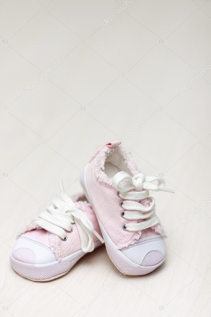 Little girlie baby shoes on a wooden floor, copy space for text